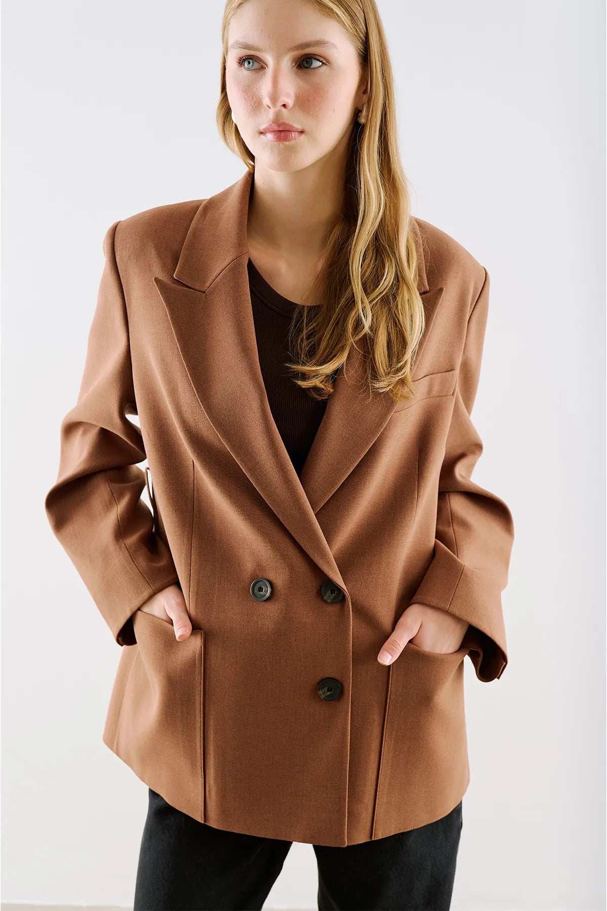 A camel double-breasted blazer worn open over a black top.