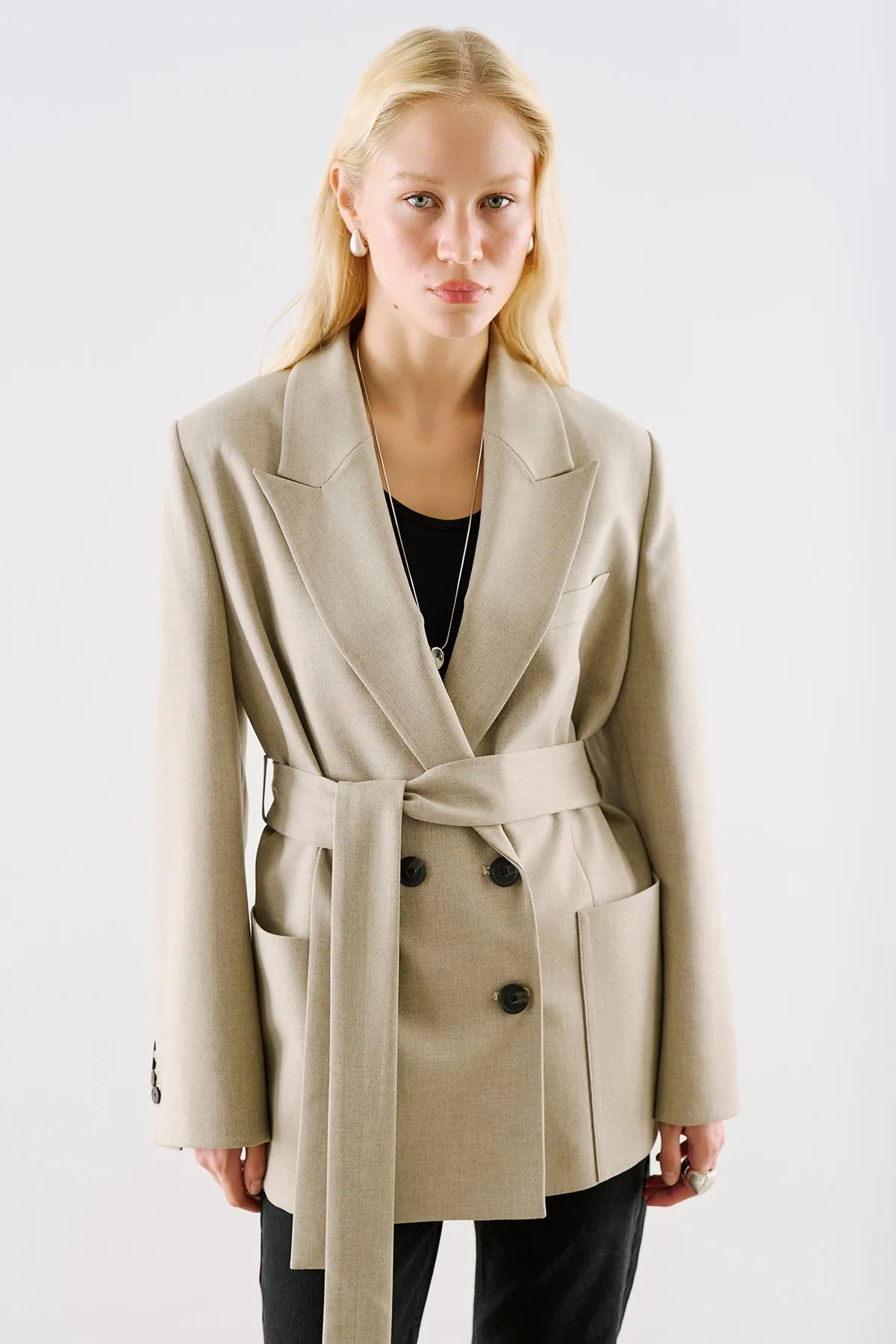 A cream belted blazer with patch pockets and a wide notch lapel.
