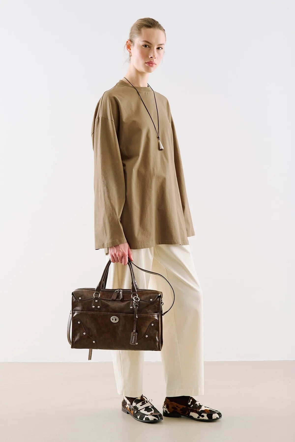 A sand-coloured tunic with long sleeves, worn over cream trousers.