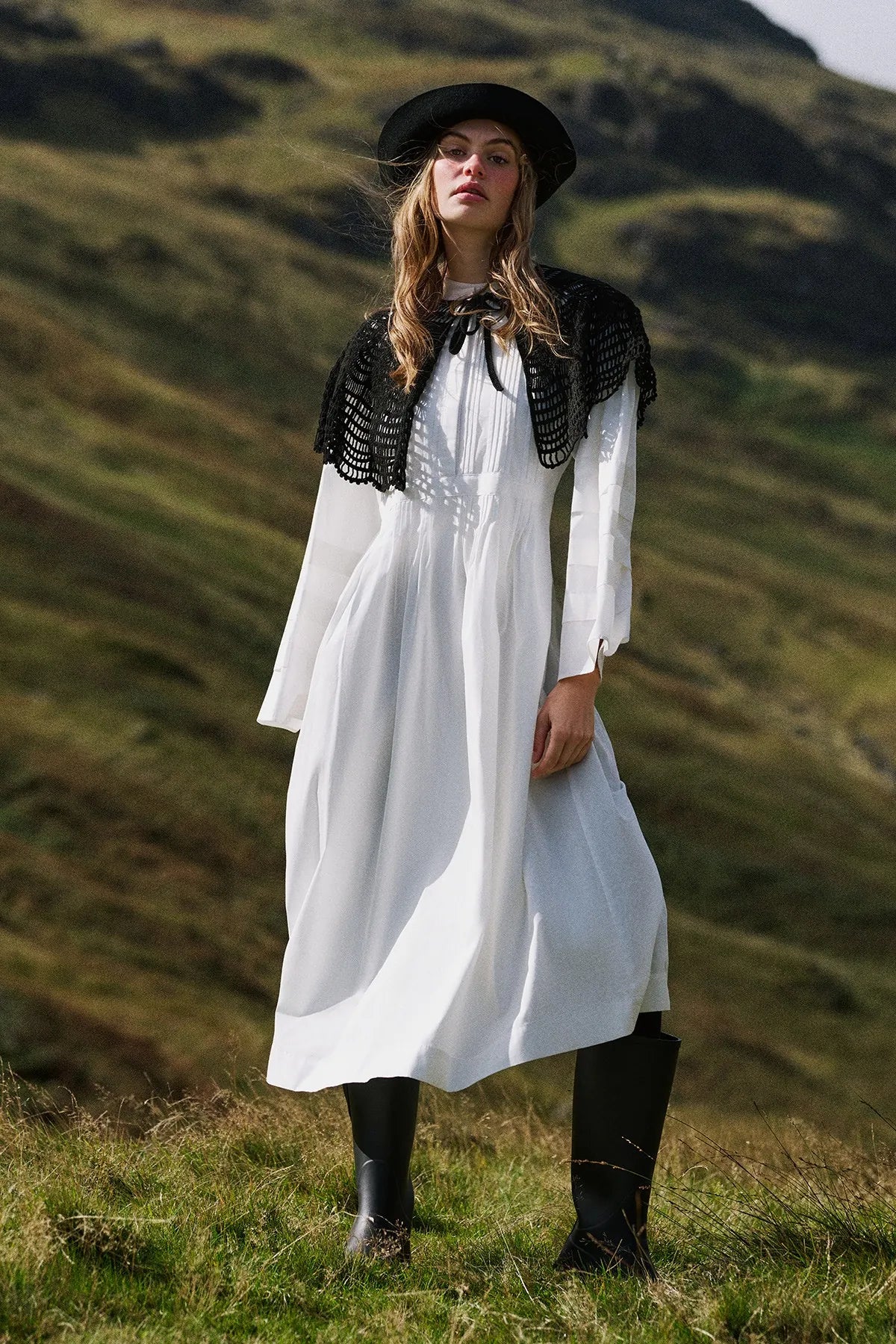 A white tiered dress with a black lace shawl, on a hillside in autumn light.